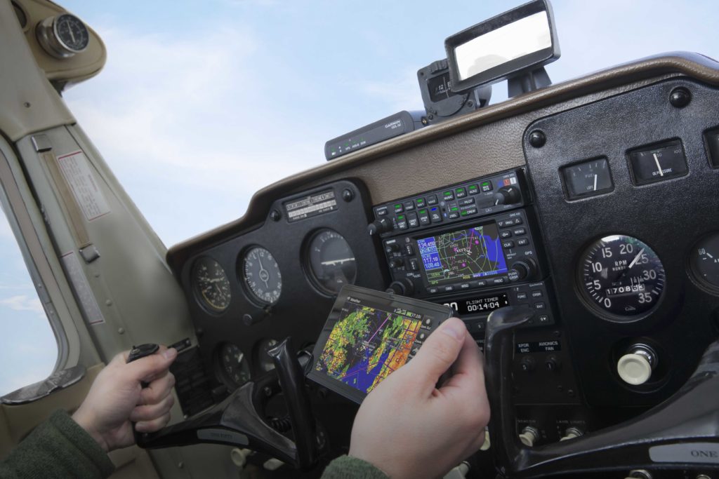GDL 52 on top of aircraft panel with pilot holding aera 660 in flight
