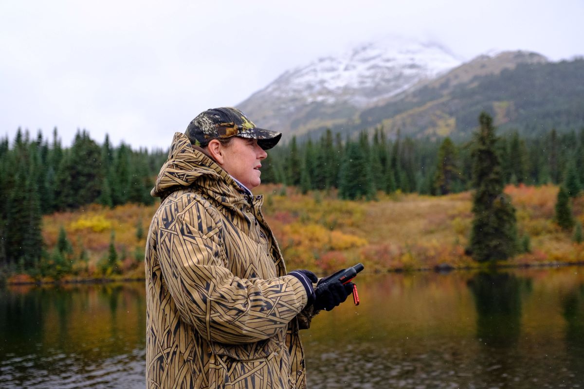 Man standing by mountain holding inReach sattelite messenger.