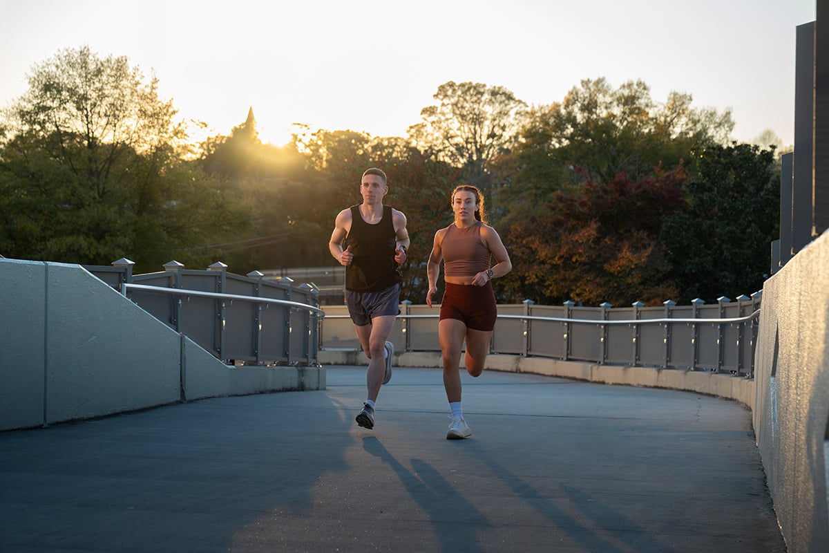 A man and woman wearing Garmin smartwatches run along a path.