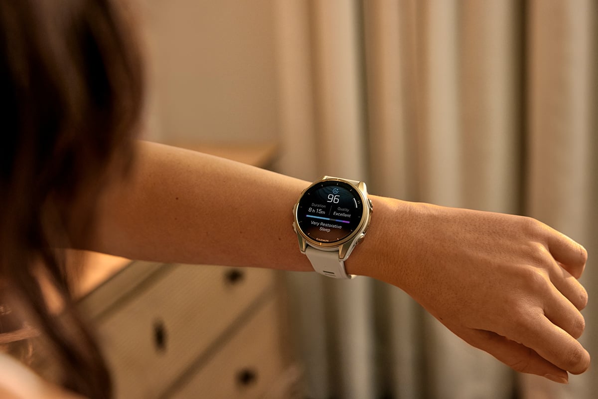 A woman wearing a Garmin smartwatch checks her sleep score of 96.