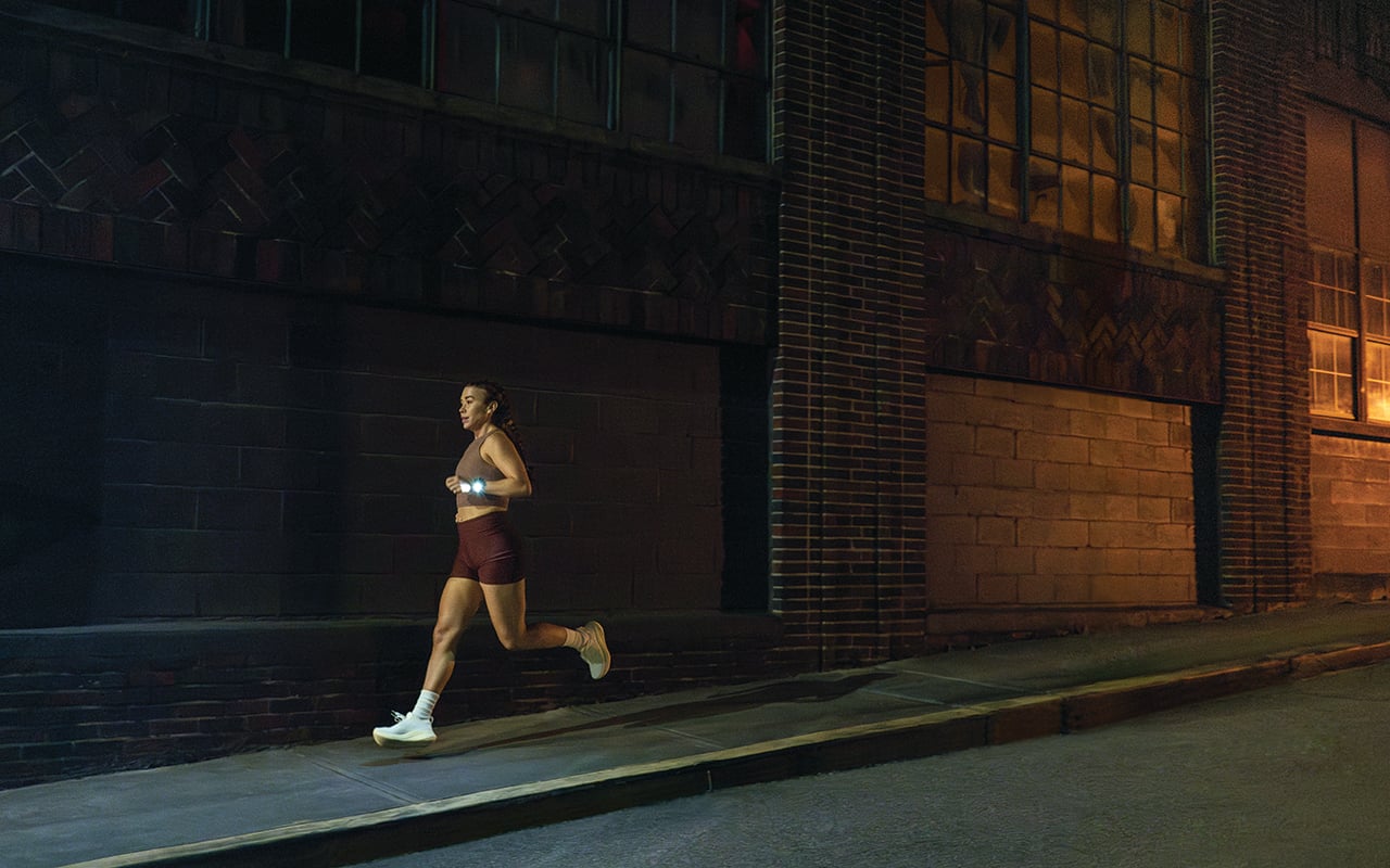 Woman running in the dark with her Garmin smartwatch flashlight on.