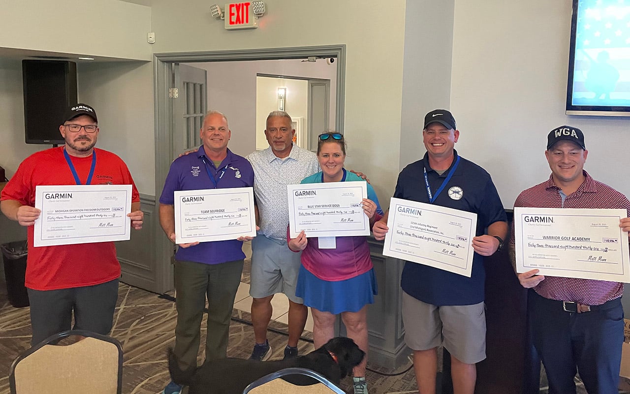 Military charities pose with checks raised by Garmin and suppliers at a recent corporate event in Novi, Michigan.