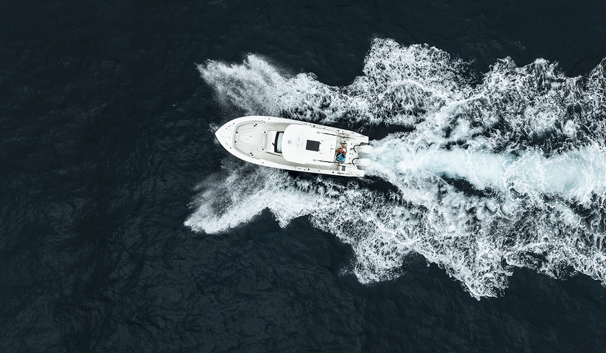 Overhead view of a boat sailing on the ocean with waves on either side.