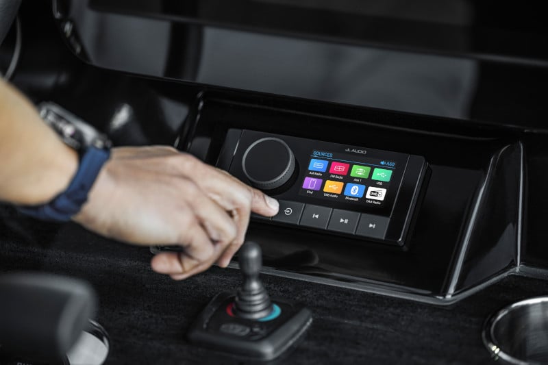 Someone reaching to control the settings on their JL Audio A60 head unit.